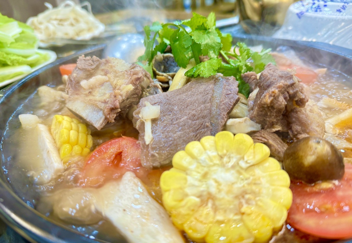 A steaming bowl of yak meat hotpot with vegetables