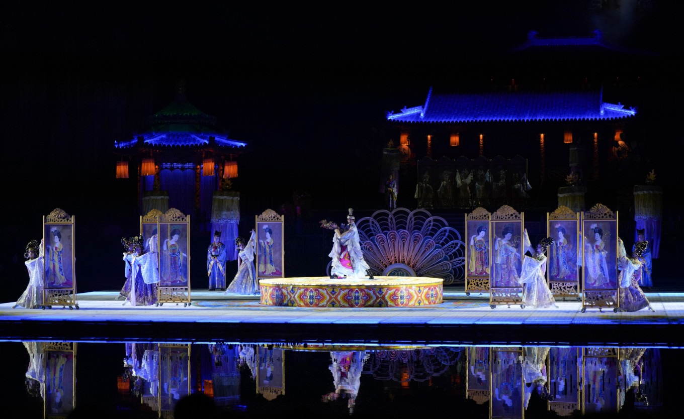 Dancers in Tang Dynasty costumes performing on stage with fireworks