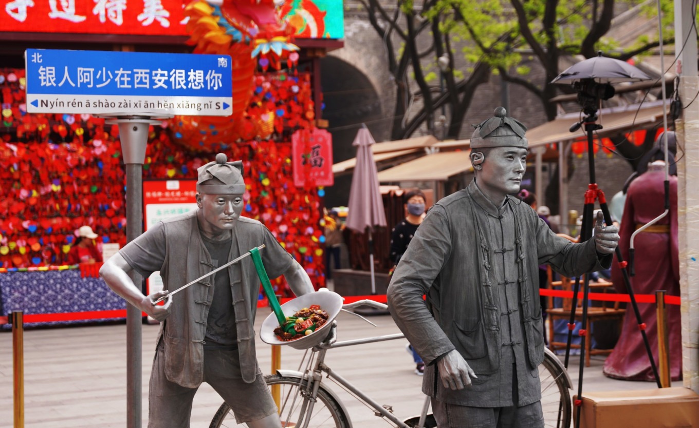 Silver-painted street performer posing with visitors at Yongxing Fang