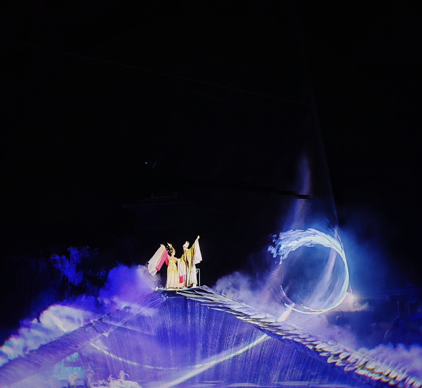Full stage view with hundreds of performers and illuminated mountain