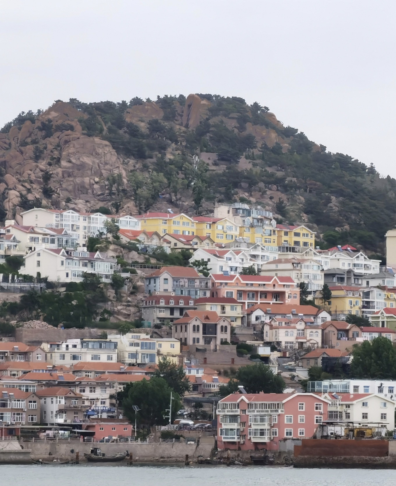 Panoramic view of Shazikou fishing village with colorful houses on hillside and sea in background