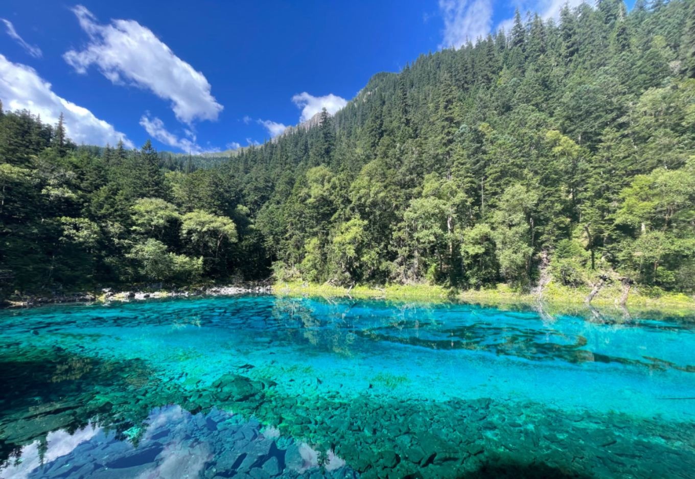 Five-Color Pond (Wucai Chi) with crystal clear water reflecting blue sky and green trees