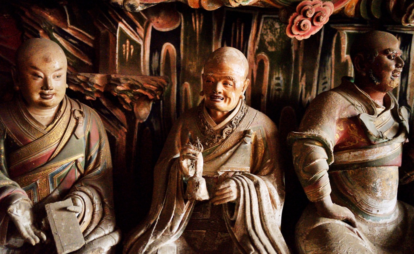 Dragon-Subduing Arhat staring at dragon sculpture