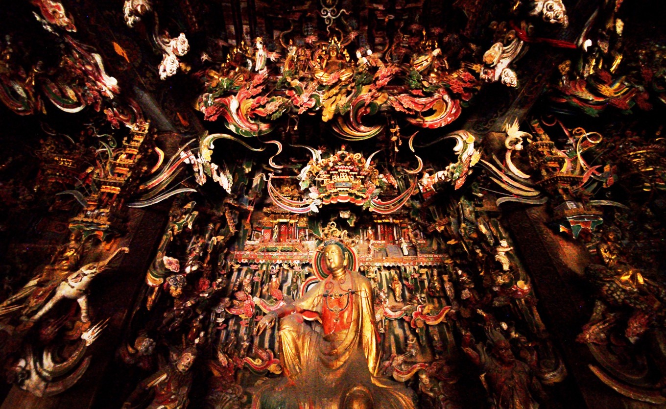 Interior of Guanyin Hall main hall showing dense hanging sculptures covering walls and beams