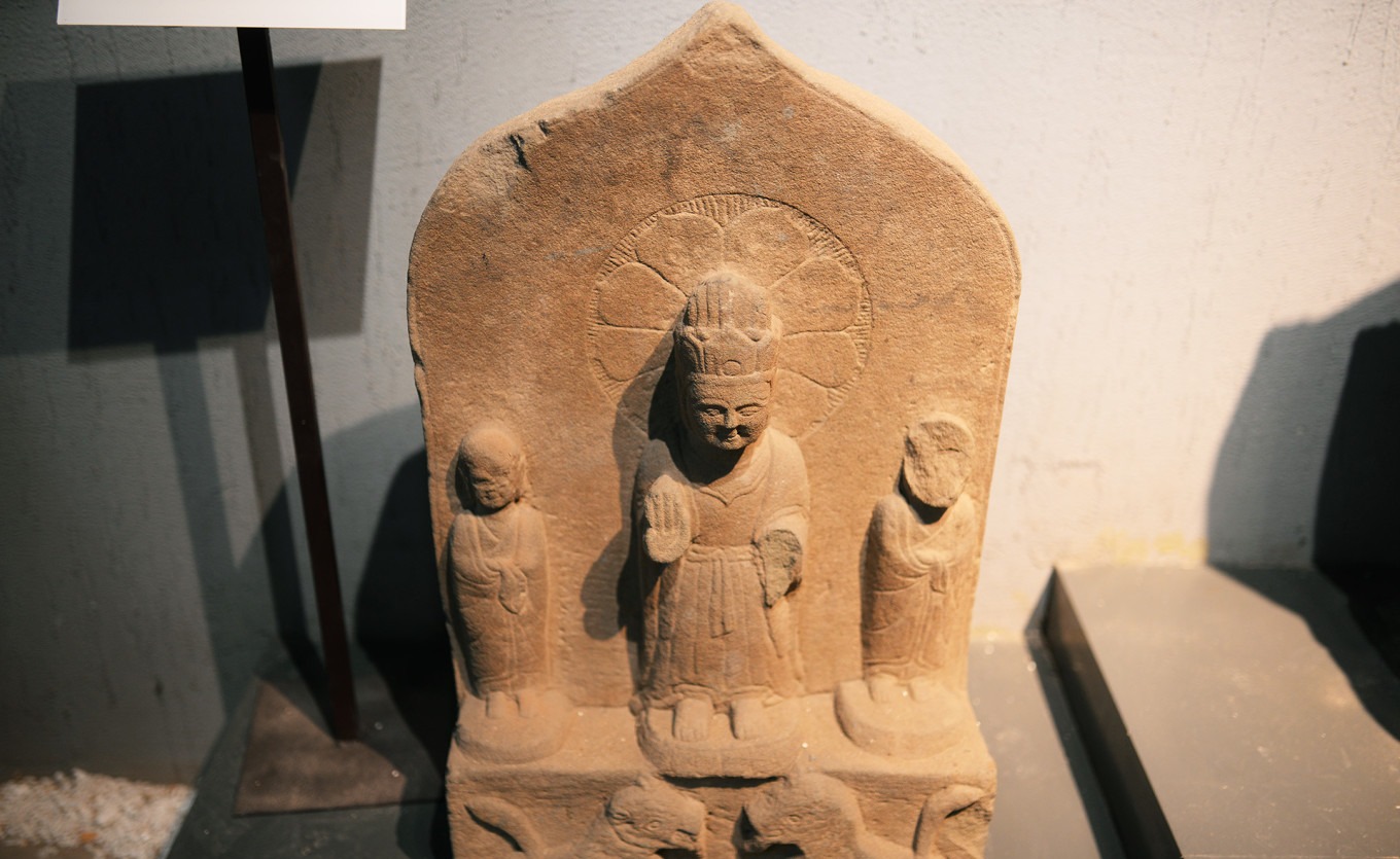 Stone carving with Buddha above and lotus and guardian figures below