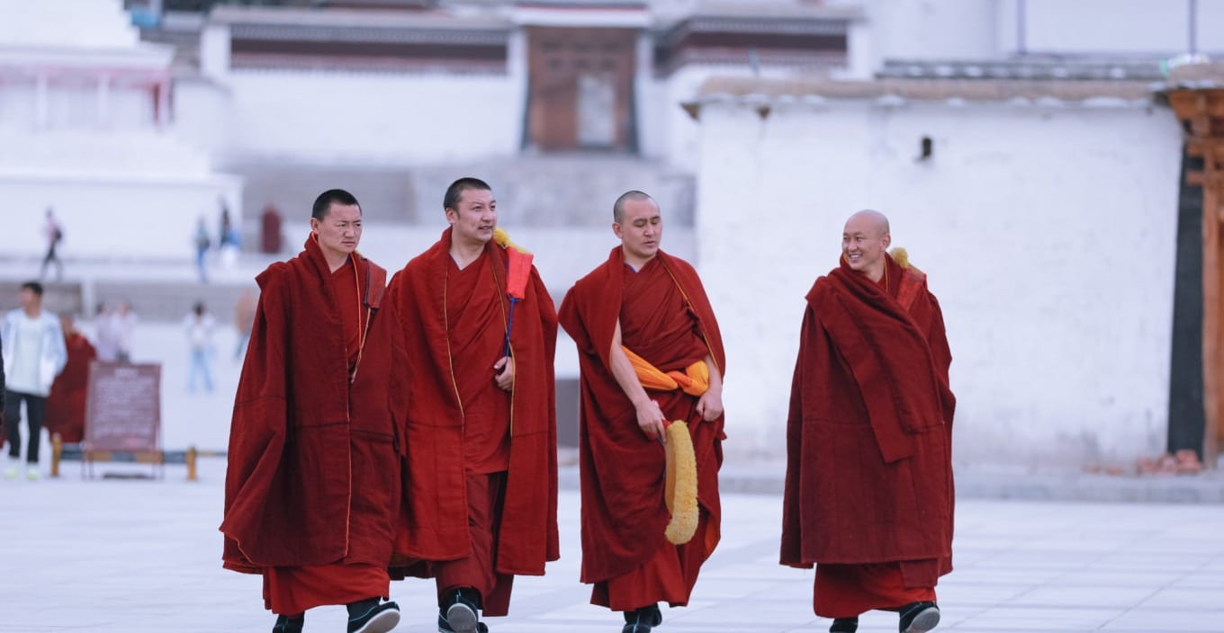 Monk standing solemnly in front of a white wall