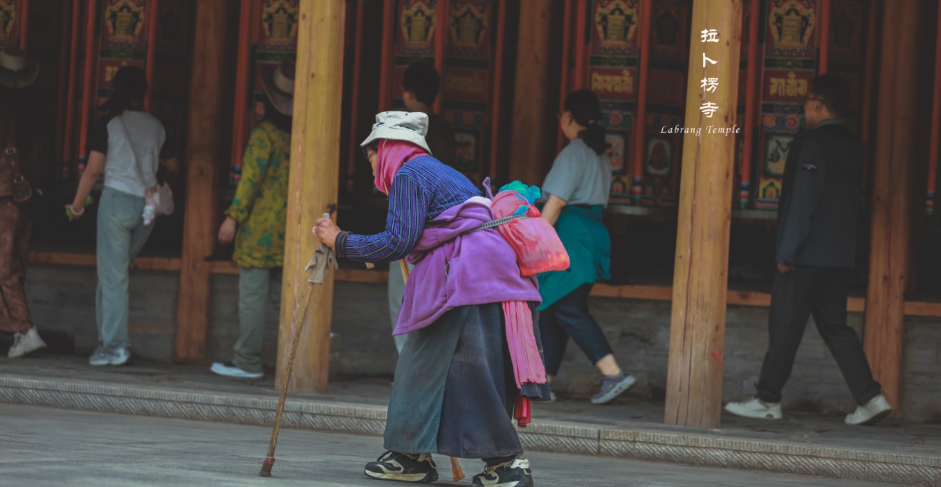 Diverse group of pilgrims including elderly and young people turning prayer wheels