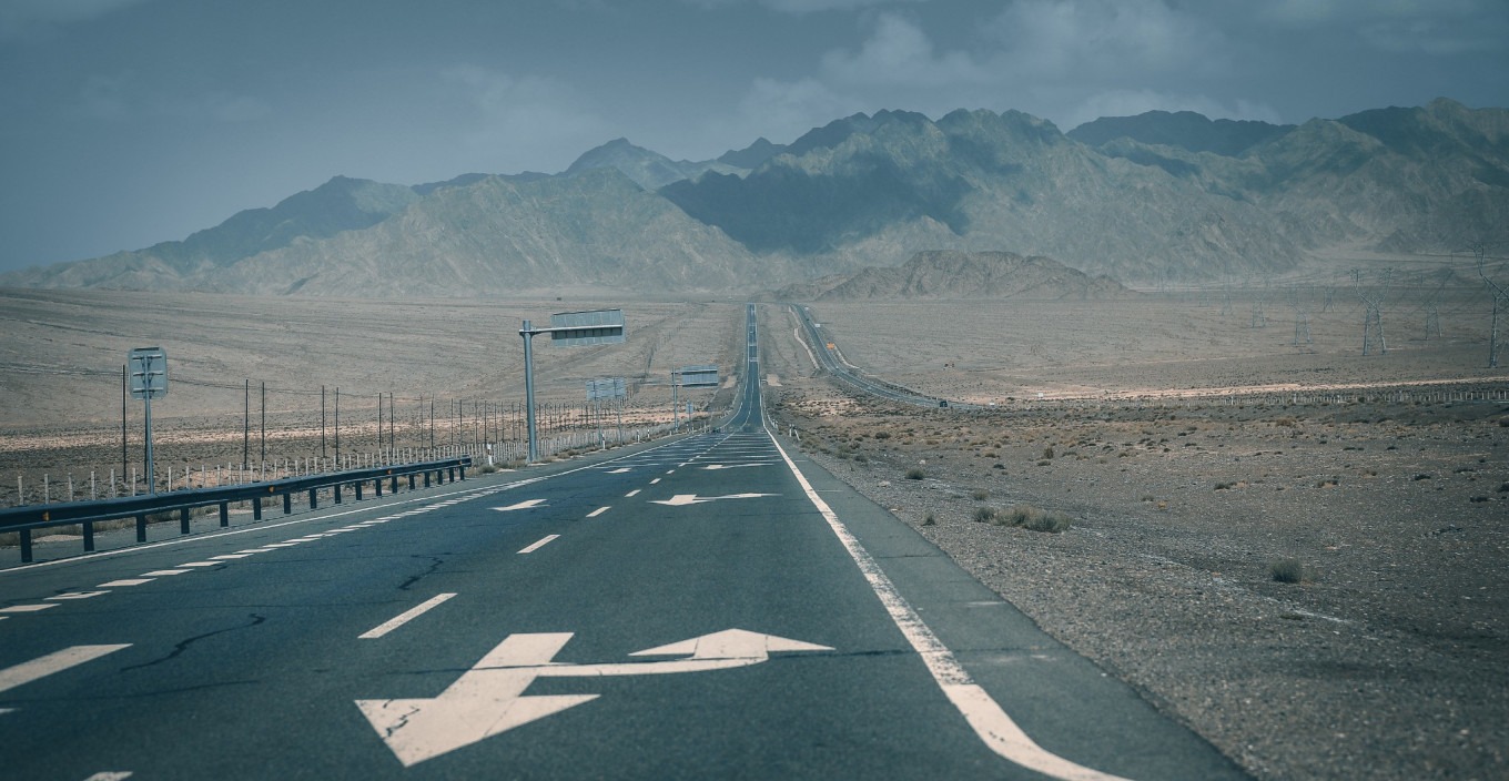 Road stretching through desert with distant mountains