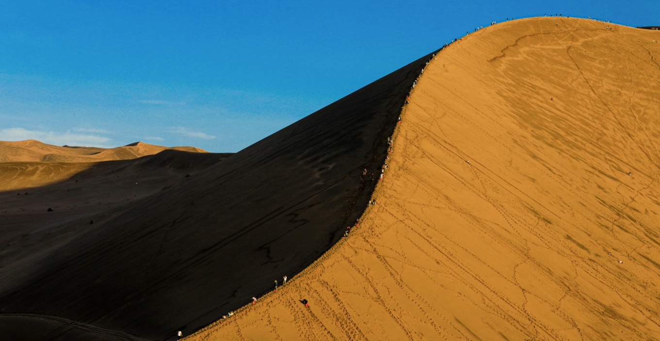 Crescent Moon Spring and Mingsha Mountain at sunset, with golden light on the dunes