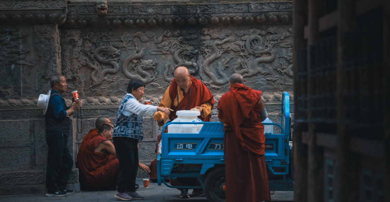 Monks distributing milk tea and flower rolls to devotees